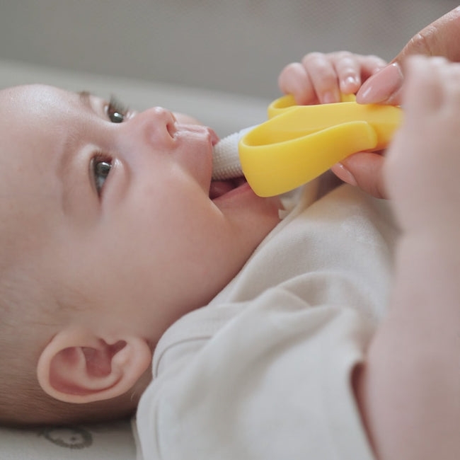 Baby holding banana teether 